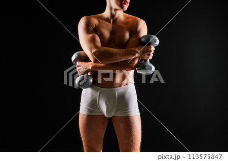 Man with a pumped-up body with dumbbells in his hands white panties exercise 113575847