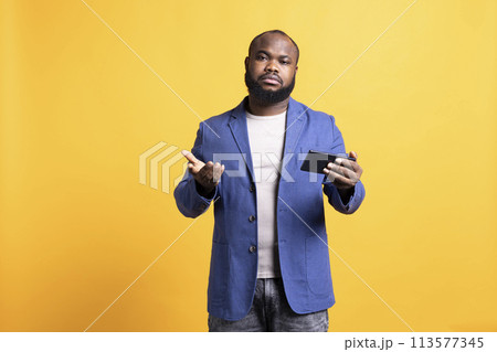 Portrait of disappointed man unhappy after receiving bad news from friend, talking on smartphone. Sad BIPOC person frowning after reading text messages on phone, studio background Portrait of disappointed man unhappy after receiving bad news from friend, talking on smartphone. Sad BIPOC person frowning after reading text messages on phone, studio background 113577345
