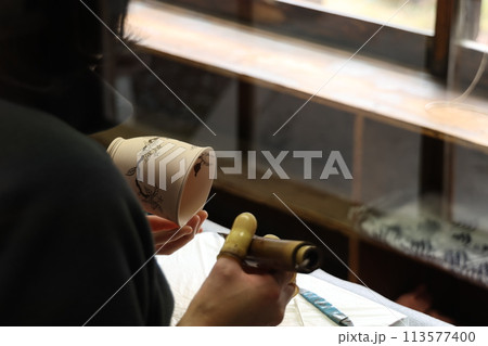 陶芸で下絵付けをする女性の手元 113577400
