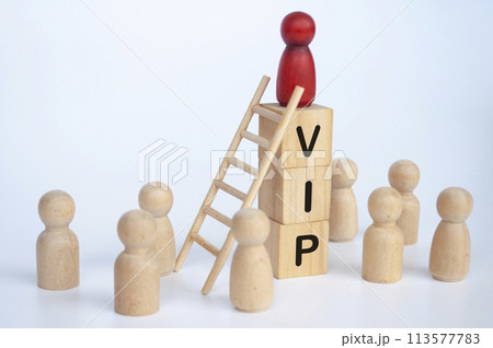 VIP text on wooden cubes with wooden dolls looking up to red figure doll 113577783
