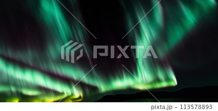Aurora australis or Aurora borealis or Green northern lights sky above mountains. Night sky with polar lights. Night winter landscape with southern lights aurora against Real Natural black background. 113578893
