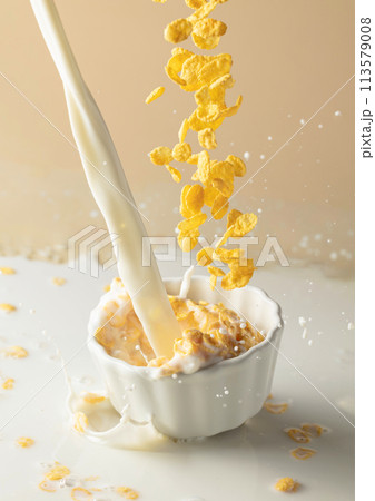 Dry honey cornflakes with milk splashes in a ceramic plate. 113579008