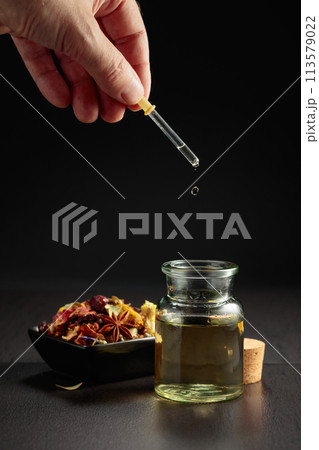 Dropping essential oil or herbal tincture into a small bottle. 113579022