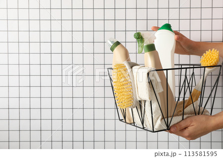 Basket with bottles of detergents and brushes in hands on light background, space for text Basket with bottles of detergents and brushes in hands on light background, space for text 113581595