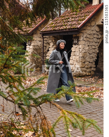 woman in autumn outfit walking by street 113583365