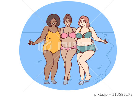 Cheerful plus size women dressed in swimsuit stand hugging on sunny beach near sea water 113585175