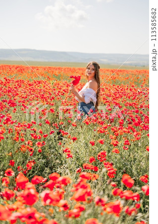 Woman poppies field. Side view of a happy woman with long hair in a poppy field and enjoying the beauty of nature in a warm summer day. 113585682