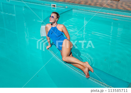 Bikini-clad woman enjoys poolside relaxation. Poolside ambiance. Capturing woman's relaxed time near pool. 113585711
