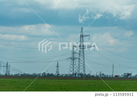 High voltage towers with sky background. Power line support with wires for electricity transmission. High voltage grid tower with wire cable at distribution station. Energy industry, energy saving High voltage towers with sky background. Power line support with wires for electricity transmission. High voltage grid tower with wire cable at distribution station. Energy industry, energy saving 113585911