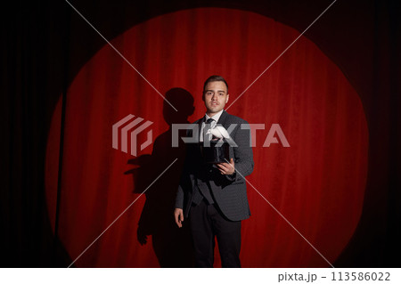 Elegant mysterious illusionist showing tricks with rabbit Elegant mysterious illusionist showing tricks with rabbit 113586022
