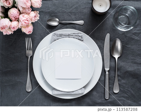 Menu, wedding invitation mock up. Beautiful table setting on gray linen tablecloth. Festive table setting for wedding dinner with pink spray roses and cabdle. Holiday dinner, white plates. Copy space Menu, wedding invitation mock up. Beautiful table setting on gray linen tablecloth. Festive table setting for wedding dinner with pink spray roses and cabdle. Holiday dinner, white plates. Copy space 113587208