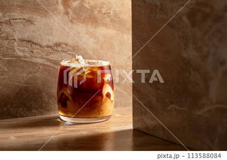 Iced coffee with cream on a beige ceramic table. Iced coffee with cream on a beige ceramic table. 113588084