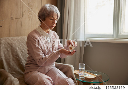 Elderly lady taking pills from chronic disease or multivitamins for health 113588169
