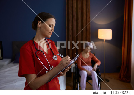 Doctor caregiver making notes about old senior woman patient Doctor caregiver making notes about old senior woman patient 113588223