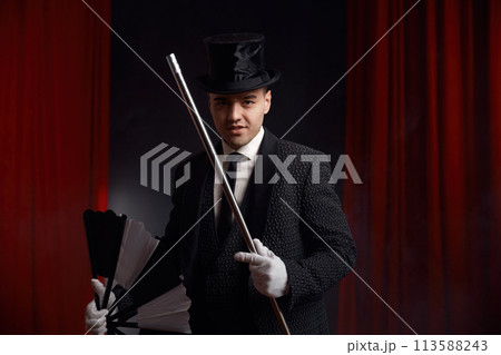 Magician performing miracle trick on stage using fan and cane 113588243