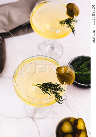Refreshing pickles martini cocktails in glasses on the table vertical view 113588324
