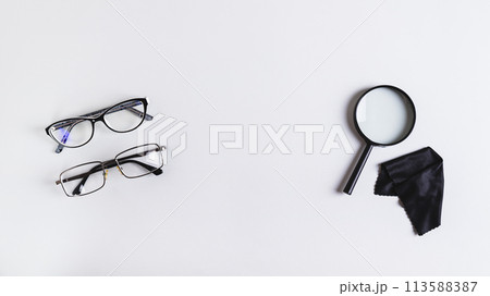Pair of eyeglasses, magnifier and cleaning cloth on blue background top view web banner Pair of eyeglasses, magnifier and cleaning cloth on blue background top view web banner 113588387