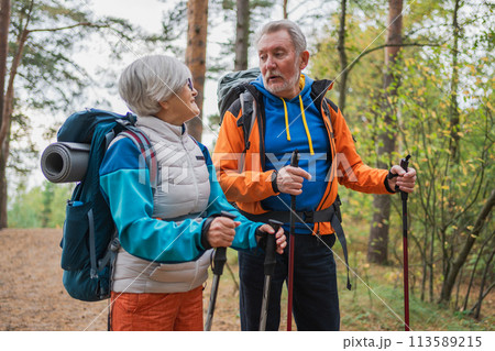 Hiking tourism adventure. Senior couple man woman enjoying outdoor recreation hiking in forest. Happy old people backpackers hikers enjoy walking hike trekking tourism active vacation beauty of nature Hiking tourism adventure. Senior couple man woman enjoying outdoor recreation hiking in forest. Happy old people backpackers hikers enjoy walking hike trekking tourism active vacation beauty of nature 113589215