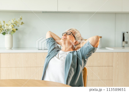 Senior old woman feeling relaxed stretching arms in kitchen at home. Smiling mature woman stretching hands feel positive optimistic fresh on bright morning new day. Good mood happy elderly lifestyle Senior old woman feeling relaxed stretching arms in kitchen at home. Smiling mature woman stretching hands feel positive optimistic fresh on bright morning new day. Good mood happy elderly lifestyle 113589651