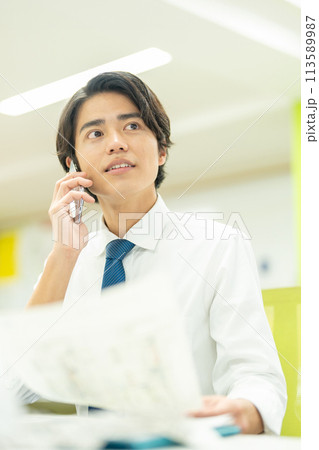 オフィスで電話する若いビジネスマン オフィスで電話する若いビジネスマン 113589987