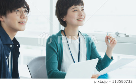 パソコンで仕事をする若い男女 113590732