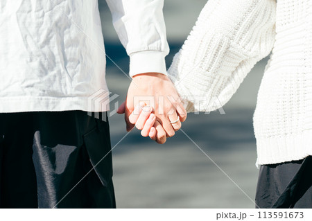 白いロングTシャツのカップルが公園で手を繋いで歩いているカップル 113591673