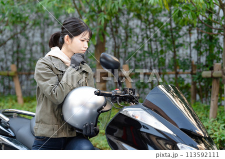 バイクに乗って悩む女性 113592111