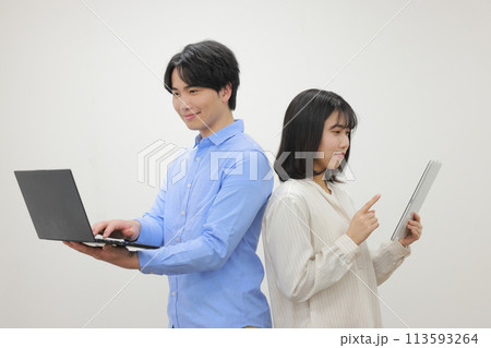 背中合わせでデバイスを操作するカジュアルな服の男女_2 背中合わせでデバイスを操作するカジュアルな服の男女_2 113593264