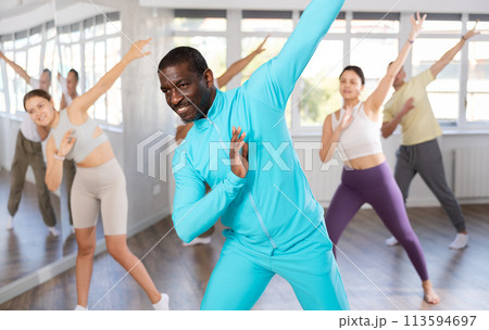 African man with team of like-minded multinational people learn to elements of contemporary dance 113594697