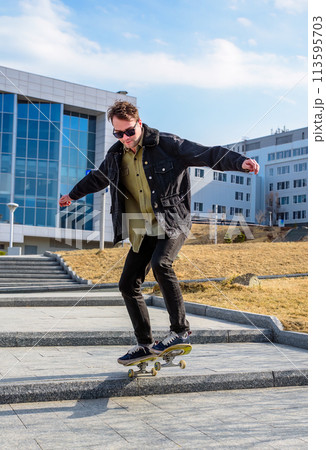 Young man riding a skateboard making tricks and jumps 113595703