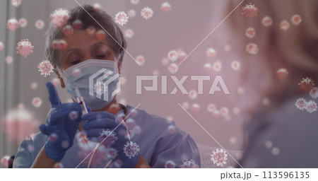 Image of covid 19 cells over female nurse preparing vaccination wearing face mask 113596135