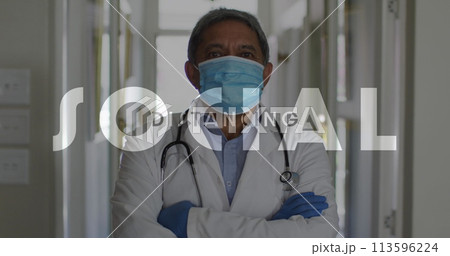 Image of social distancing text over male doctor wearing face mask 113596224