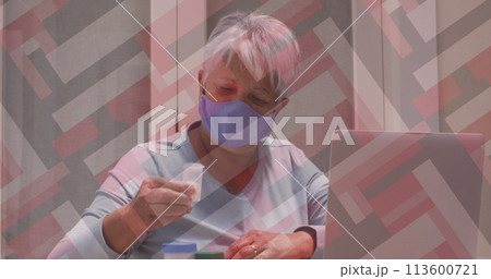 Senior biracial woman examines a medication bottle at home 113600721