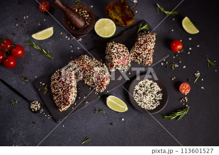 piece of tuna fillet covered with sesame seeds on a stone serving board before cooking 113601527