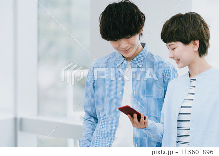 スマホを二人で見る若い男女 スマホを二人で見る若い男女 113601896
