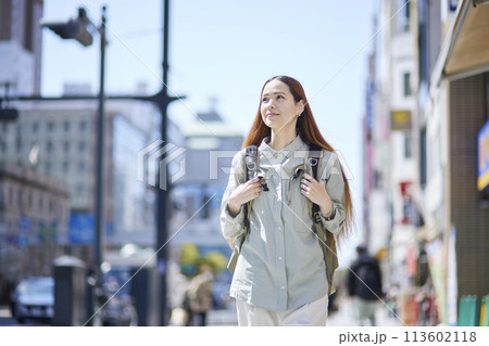 バックパックを背負って都会を歩く女性の外国人旅行者 バックパックを背負って都会を歩く女性の外国人旅行者 113602118