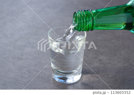 韓国の焼酎（ソジュ）をグラスに注ぐ 113603352