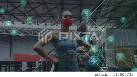 Globe of medical icons spinning against female fitness trainer wearing face mask standing in the gym Globe of medical icons spinning against female fitness trainer wearing face mask standing in the gym 113603733