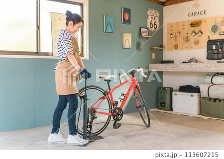 自宅の車庫でロードバイクのタイヤに空気を入れる若いアジア人女性 113607215