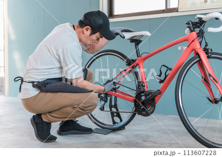 自宅のガレージでロードバイクのチェーンに給油するアジア人男性（メンテナンス・お手入れ） 113607228