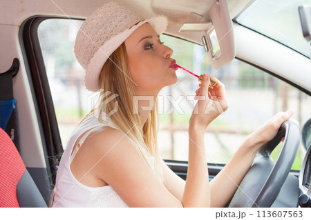 Woman applying makeup while driving her car 113607563