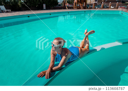 Bikini-clad woman enjoys poolside relaxation. Poolside ambiance. Capturing woman's relaxed time near pool. 113608787