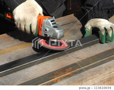 A worker processes metal with an angle grinder on a construction site. The concept of locksmith work, processing of metal products. 113610039