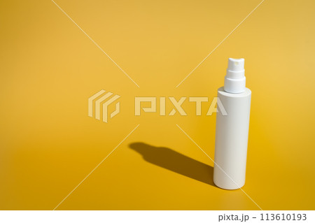 Blank white spray bottle on yellow background in direct sunlight Blank white spray bottle on yellow background in direct sunlight 113610193