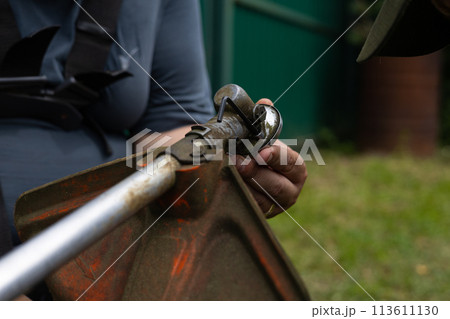 A man is repairing a grass trimmer in his yard. While cutting the grass, a man's trimmer broke and he is repairing it. Grass trimmer repair concept. 113611130