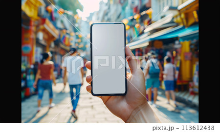 a curious tourist stands clutching a smartphone with a blank, white screen in a foreign city  113612438