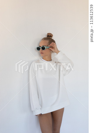 Beautiful blonde girl in a hoodie and panties posing with her back on a white background Beautiful blonde girl in a hoodie and panties posing with her back on a white background 113612539