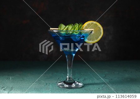 Blue cocktail with lemon and cucumber slices in glass on dark gray background, close up 113614059