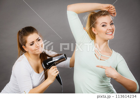 Woman drying friend armpit with hair dryer 113614234