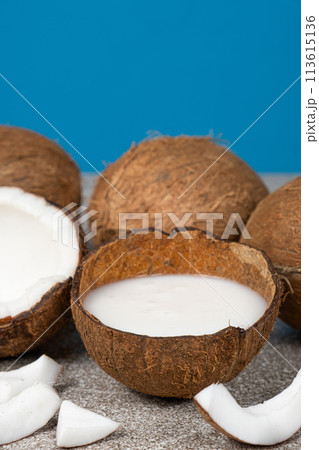 Coconut milk in coconut shell and half coconut, chopped flesh on a blue background 113615136